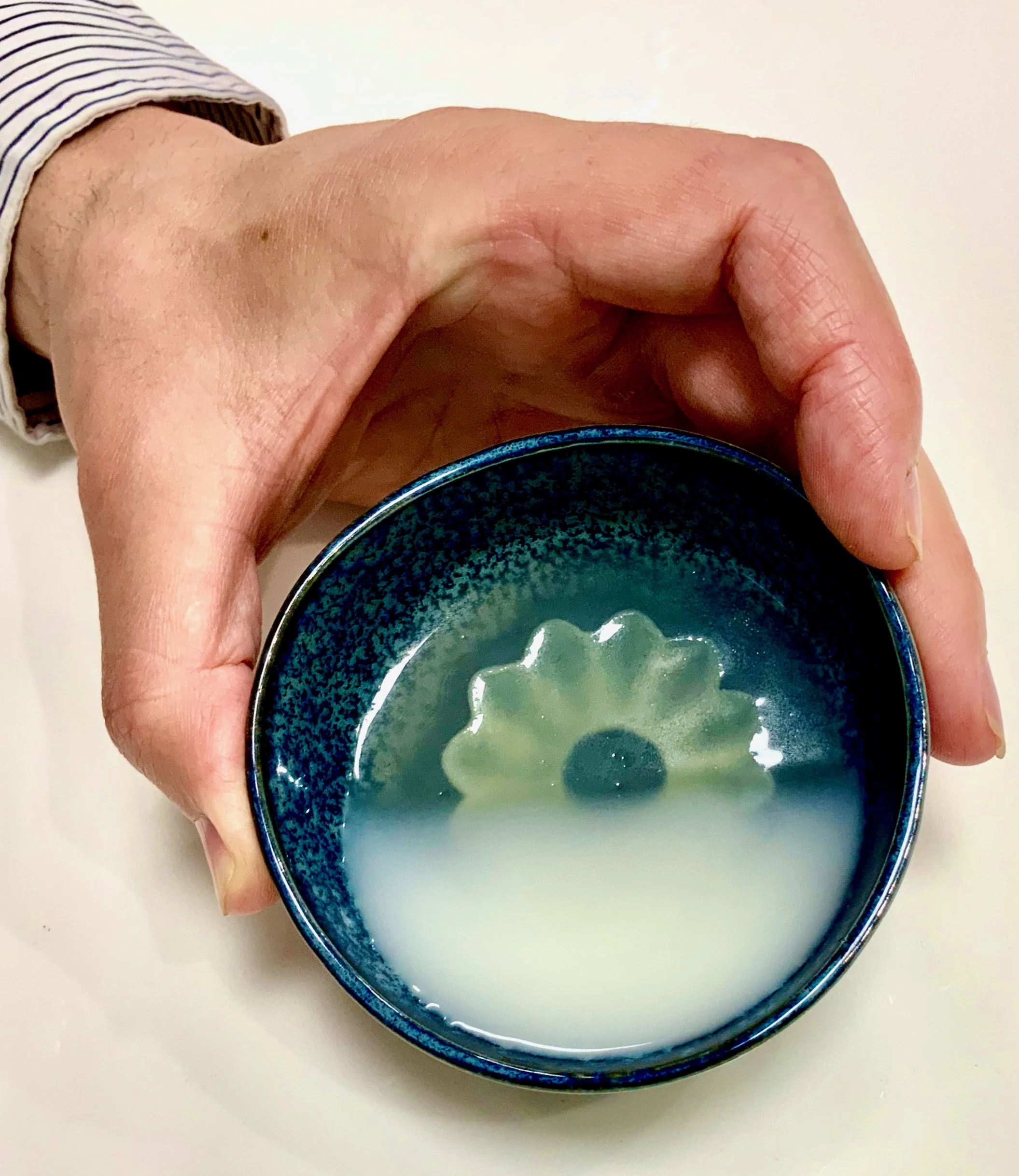 Shochu-based pre-dessert in blue Japanese-style bowl — by Chris Quirós, featuring umami gelatin and floral elements for a refined East-meets-West palate cleanser.