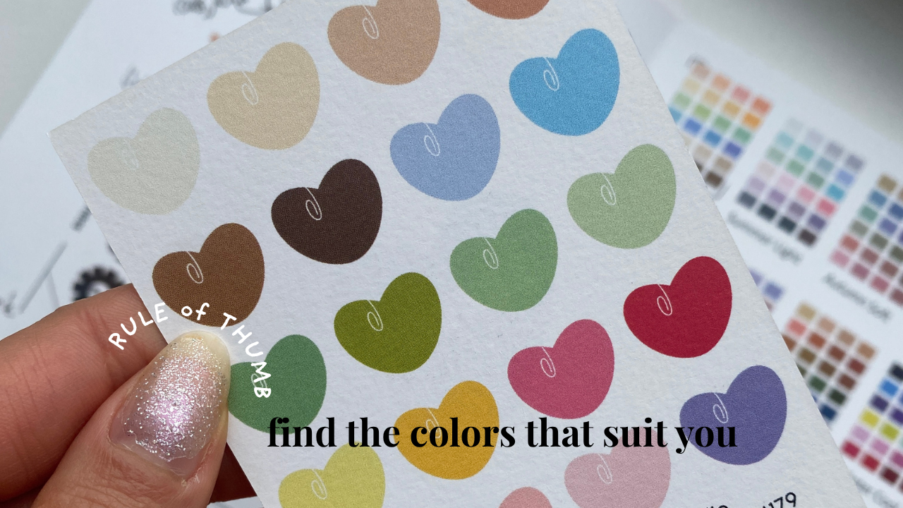 a hand holds a paper with drawings of hearts of all different kinds of colors in the warm spring palette