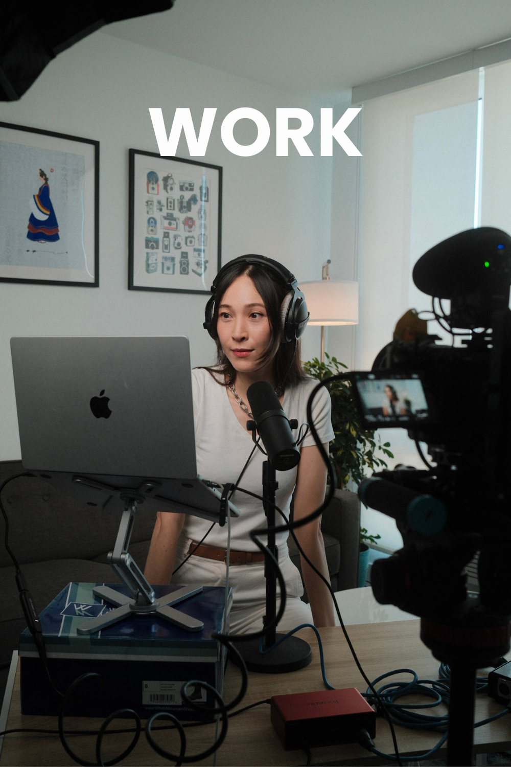 Beautiful korean voice actor wears headphones and sits in front of her laptop and camera