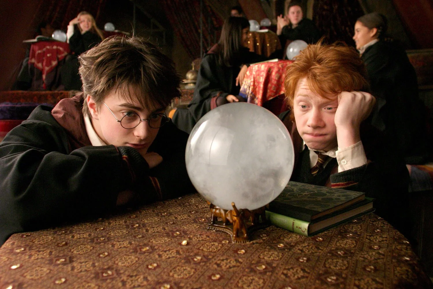 Harry Potter and ron Weasley stare in a crystal ball in Trelawney's class