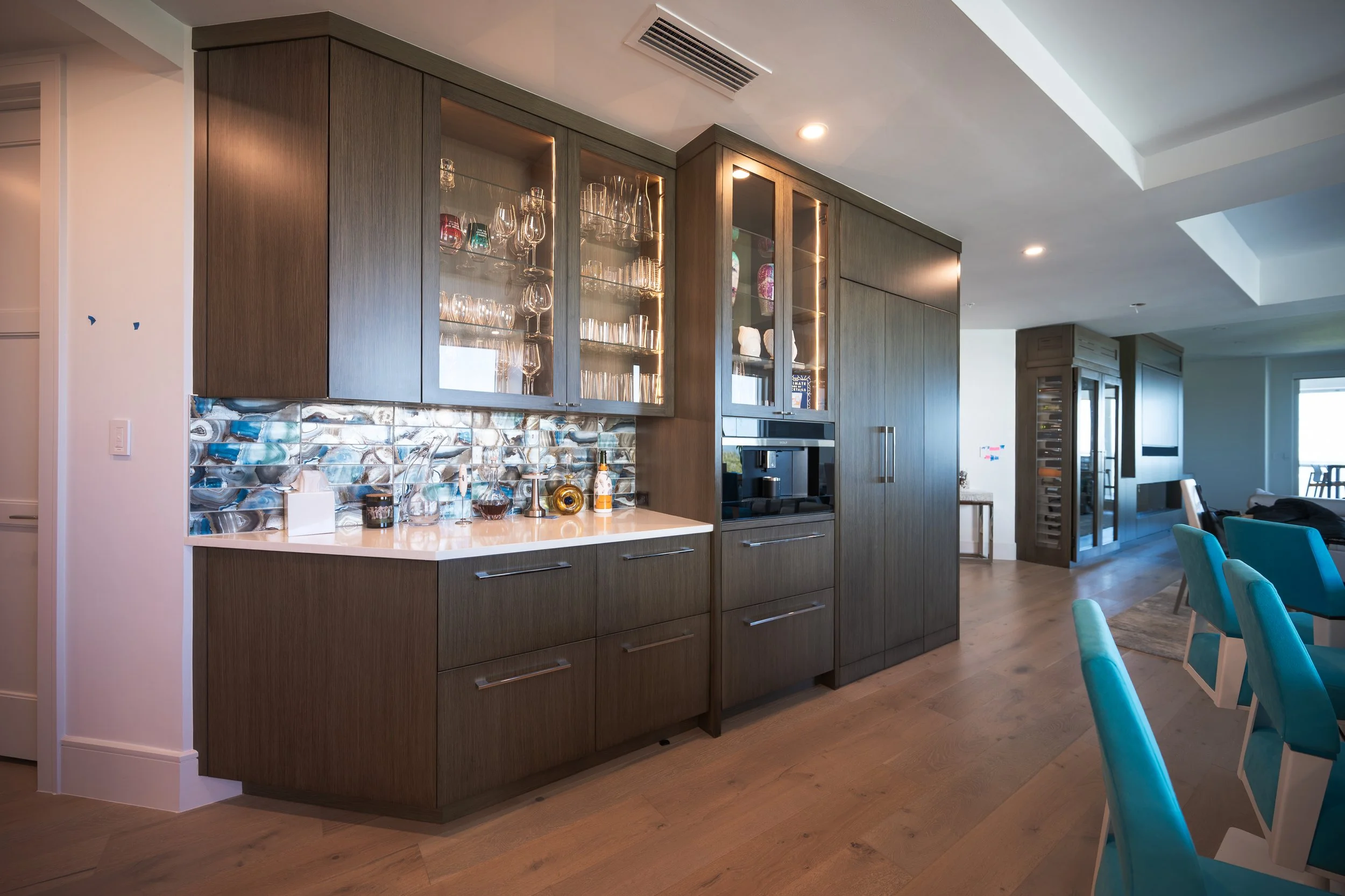 A modern kitchen with a white marble island counter and matching marble floor tiles, equipped with built-in appliances and minimalistic decor.