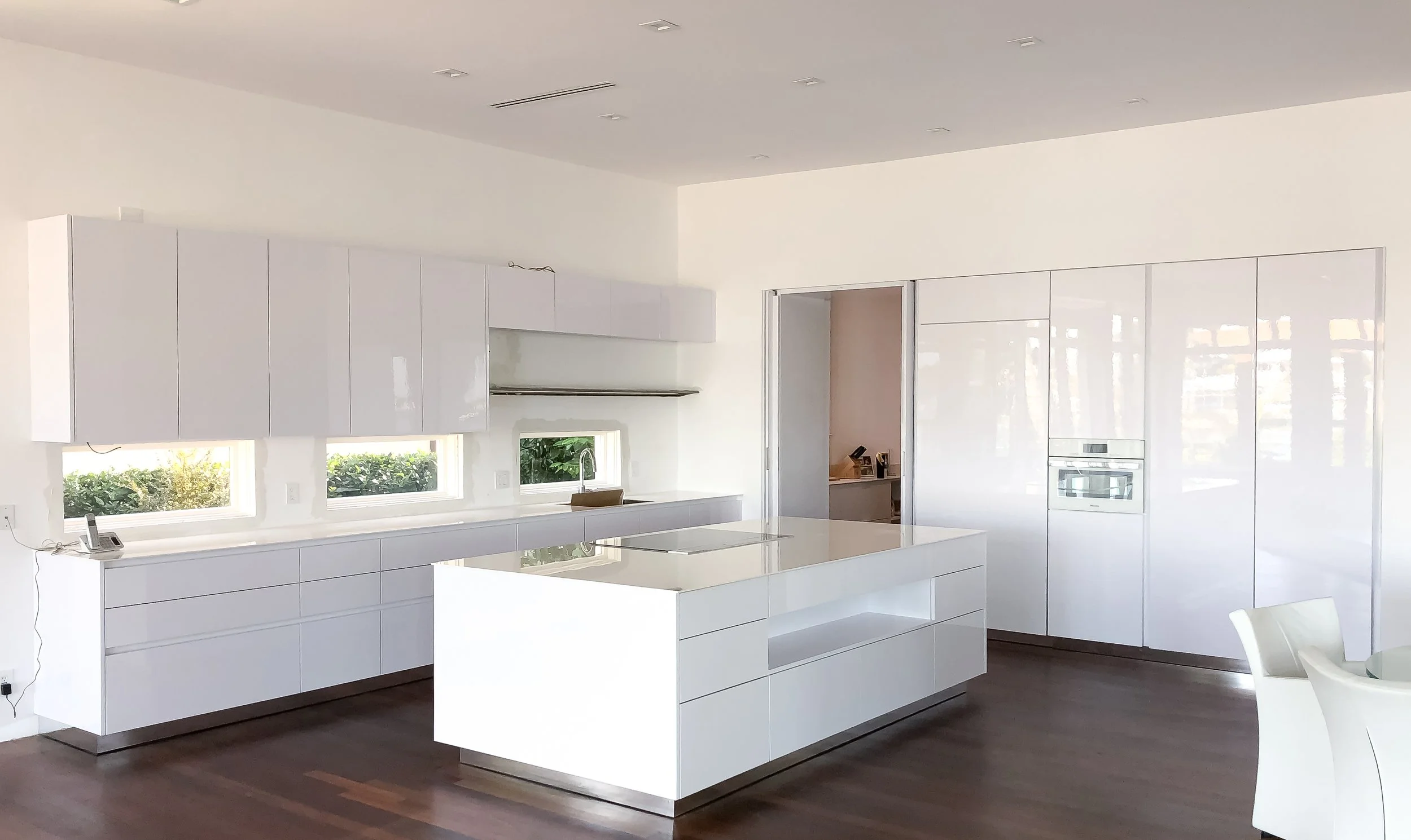 Modern kitchen with white cabinets, marble backsplash, stainless steel appliances, and light hardwood floors.