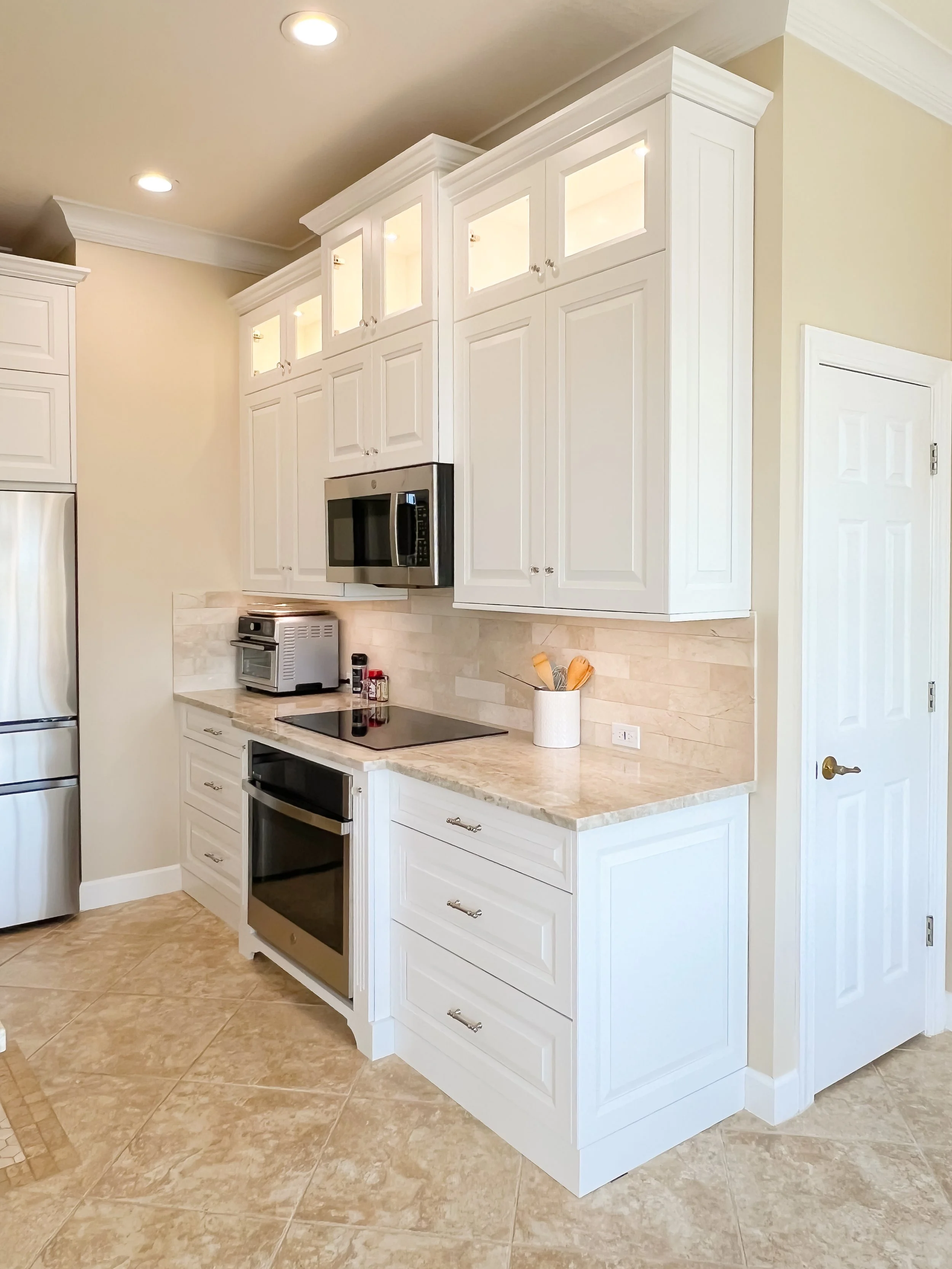 Modern bathroom vanity with white cabinets, marble countertop, and multiple mirrors with a grid design. Wall-mounted lights on either side of the mirrors, grey-painted walls, and marble flooring.