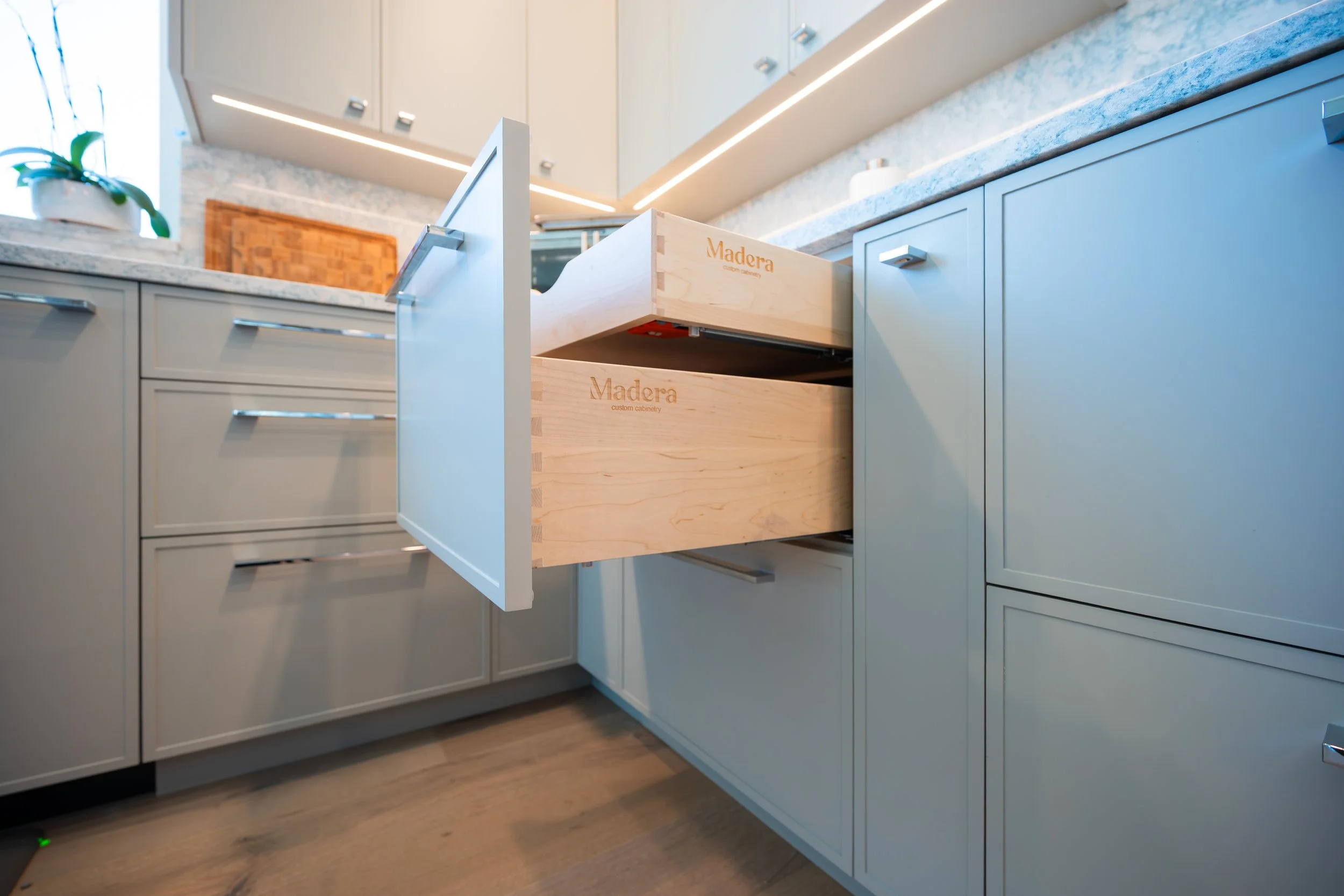 A modern kitchen with dark blue cabinets, stainless steel appliances, and a wooden kitchen island with three bar stools. 