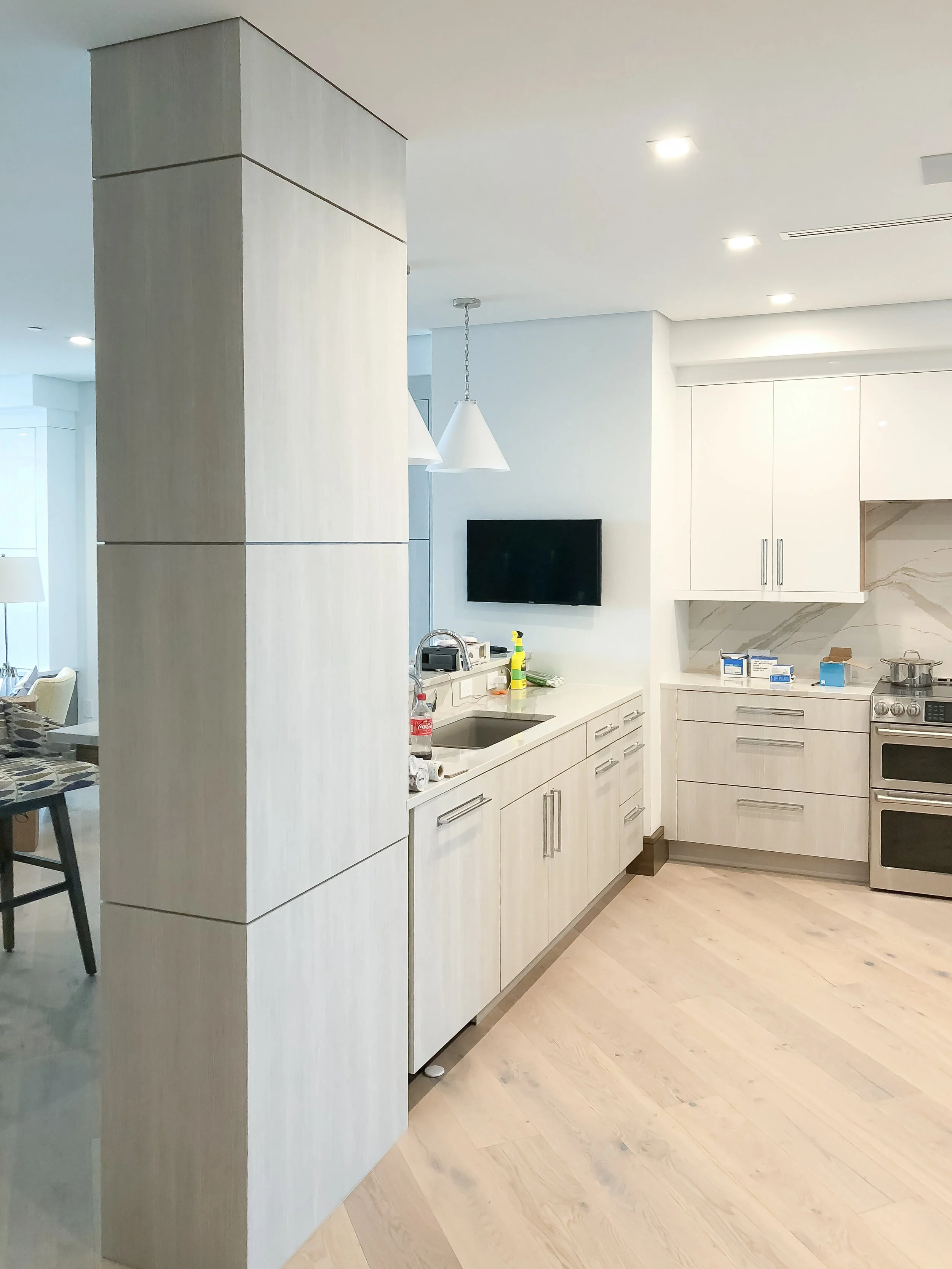 White built-in closet with drawers, cabinets, and mirror, situated in a bedroom with wood flooring and a window.