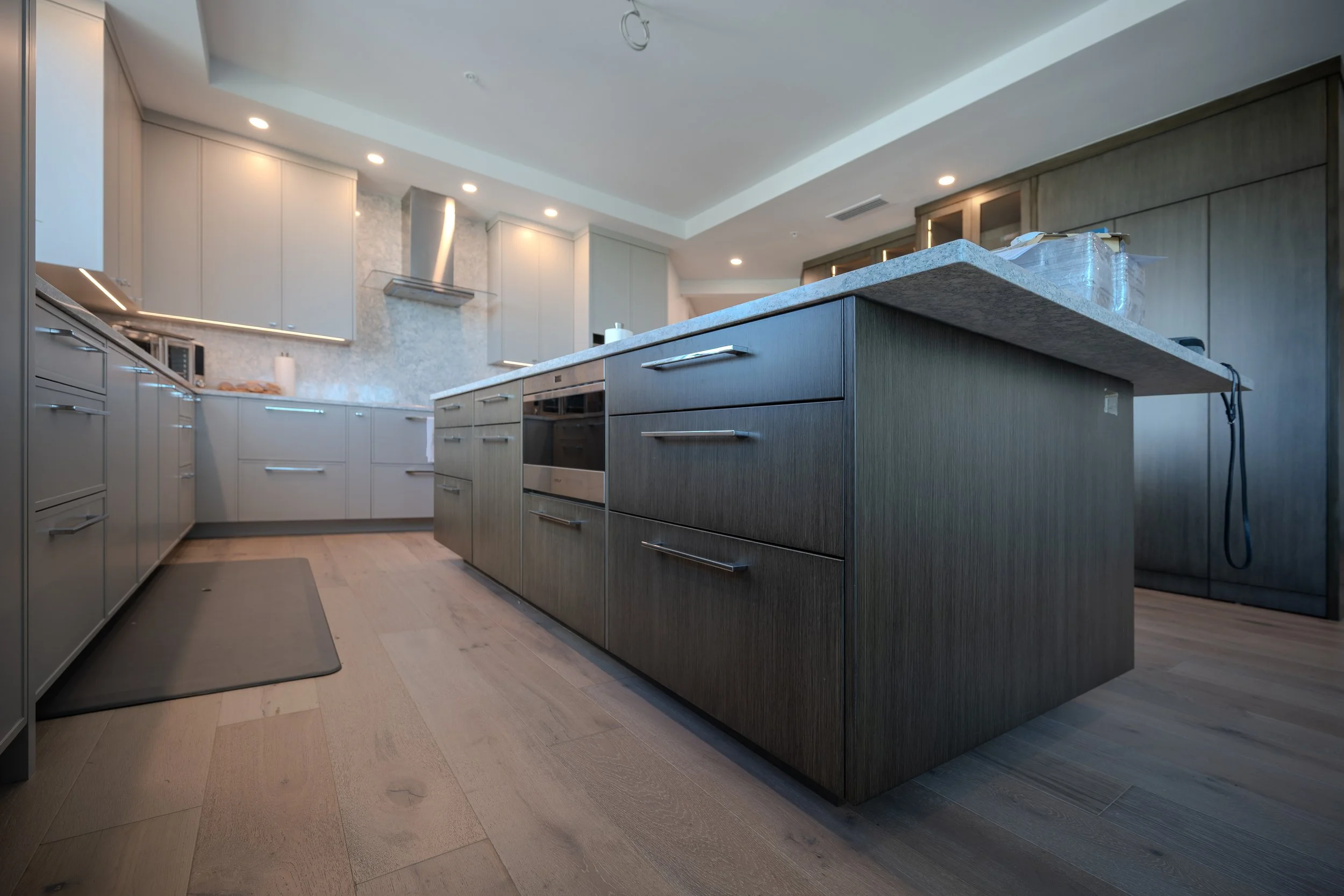 White built-in closet with vertical handles in a modern room with marble flooring and recessed ceiling lights.