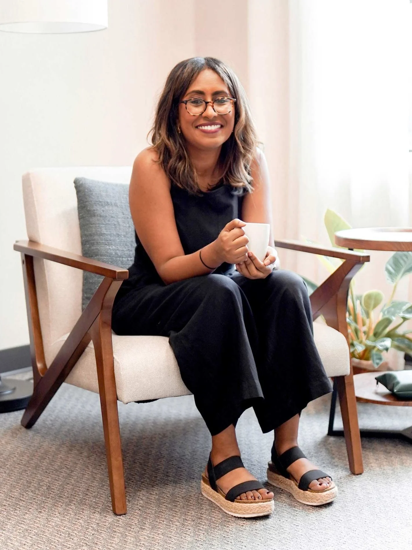 Kissu Taffere, relationship therapist in Houston, sitting in her office holding a coffee mug and smiling warmly.