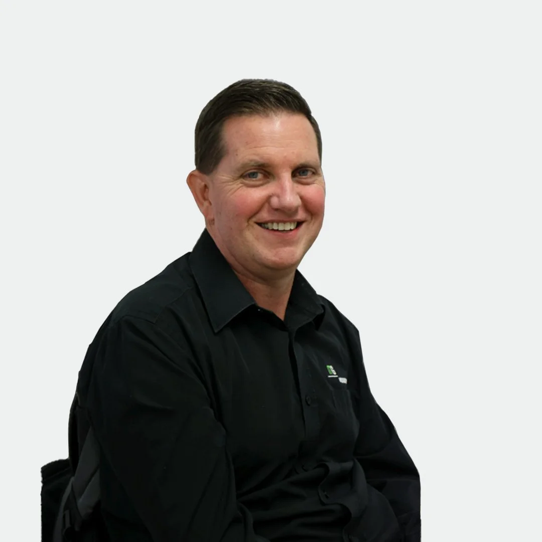 A smiling man in a black collared shirt sitting against a plain white background.