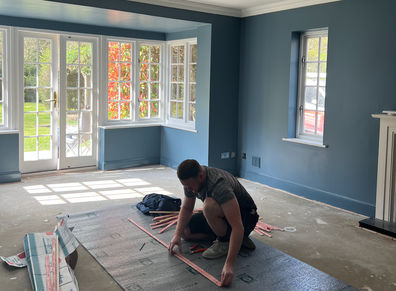 Tradesman installing natural sisal flooring in a residential home renovation project in the United Kingdom.