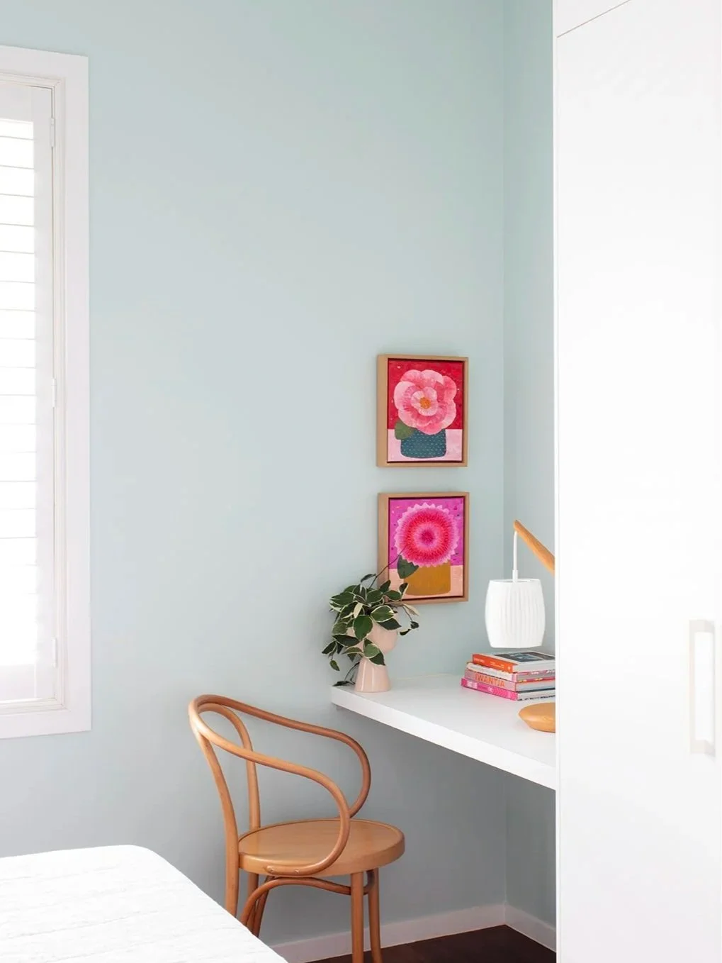 vibrant artwork in hot pinks in guest room painted in a frost green