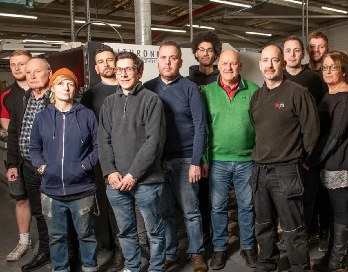 Group of people posing in a workshop or industrial setting.