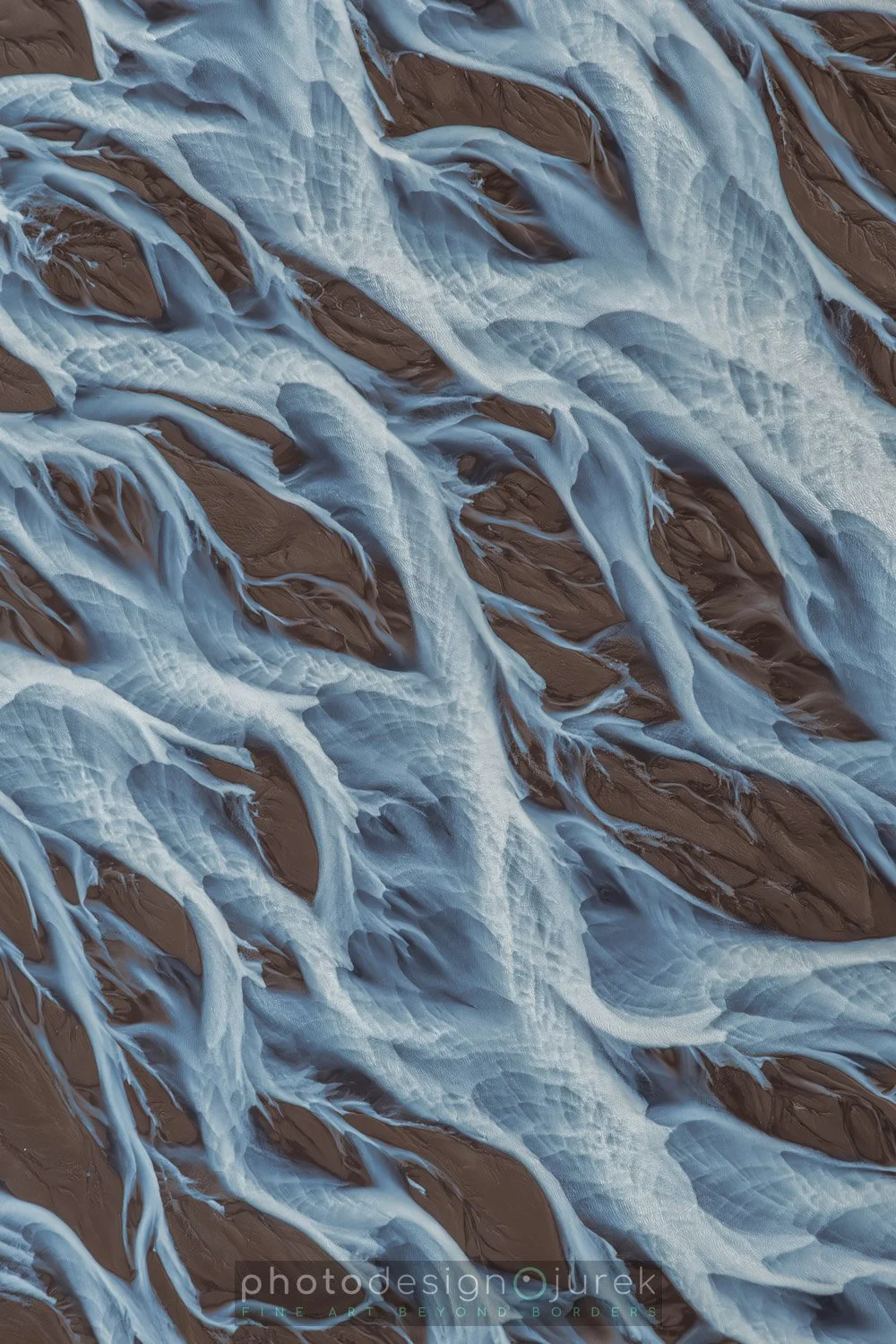 Close-up of a glacier with ice and snow flowing over dark brown rocks.