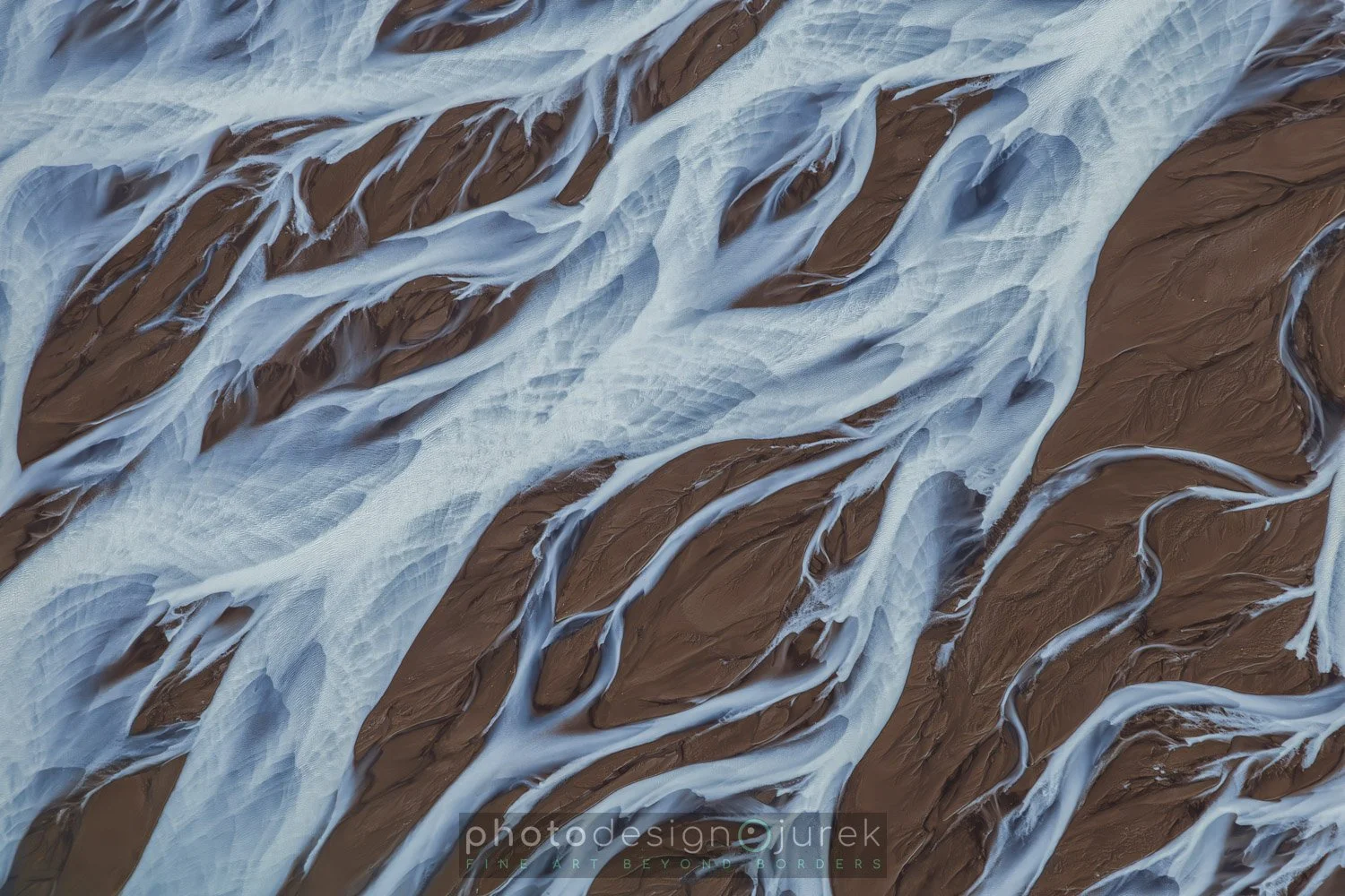 Aerial view of a river with brown water and white foam, showcasing natural erosion patterns.