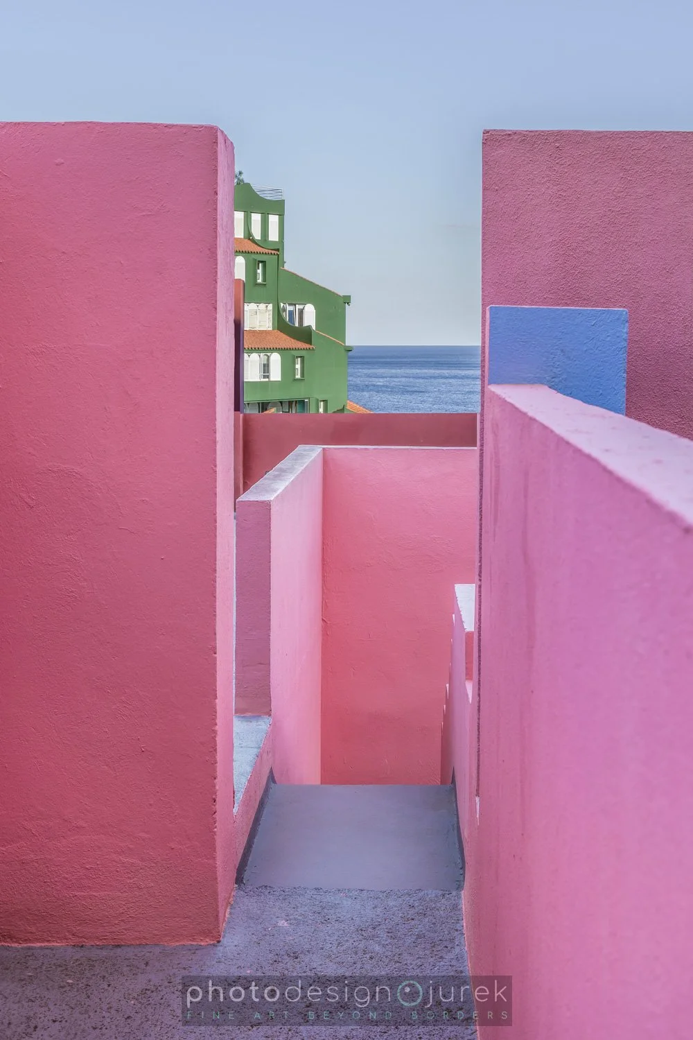 Colorful pink, blue, and green residential buildings overlooking the sea.
