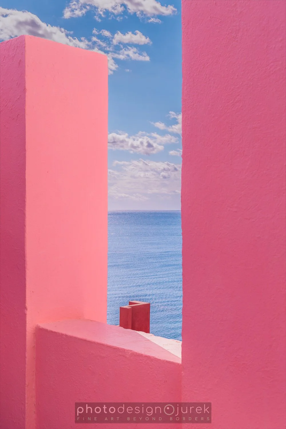 Pink walls framing a view of the ocean and a partly cloudy sky.