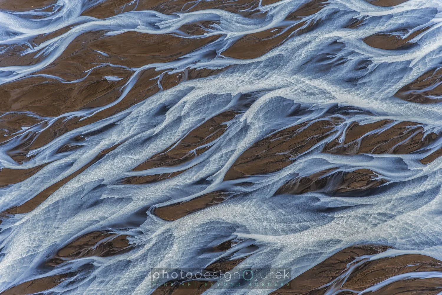 Close-up aerial view of glaciers and ice flowing over dark rocky terrain.