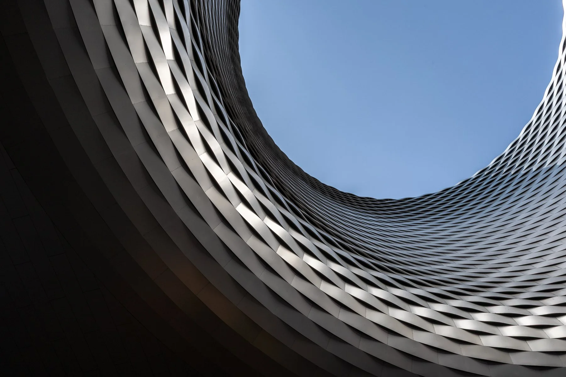 Modern minimalist building with a large floating concrete cube and rectangular windows against a blue sky.