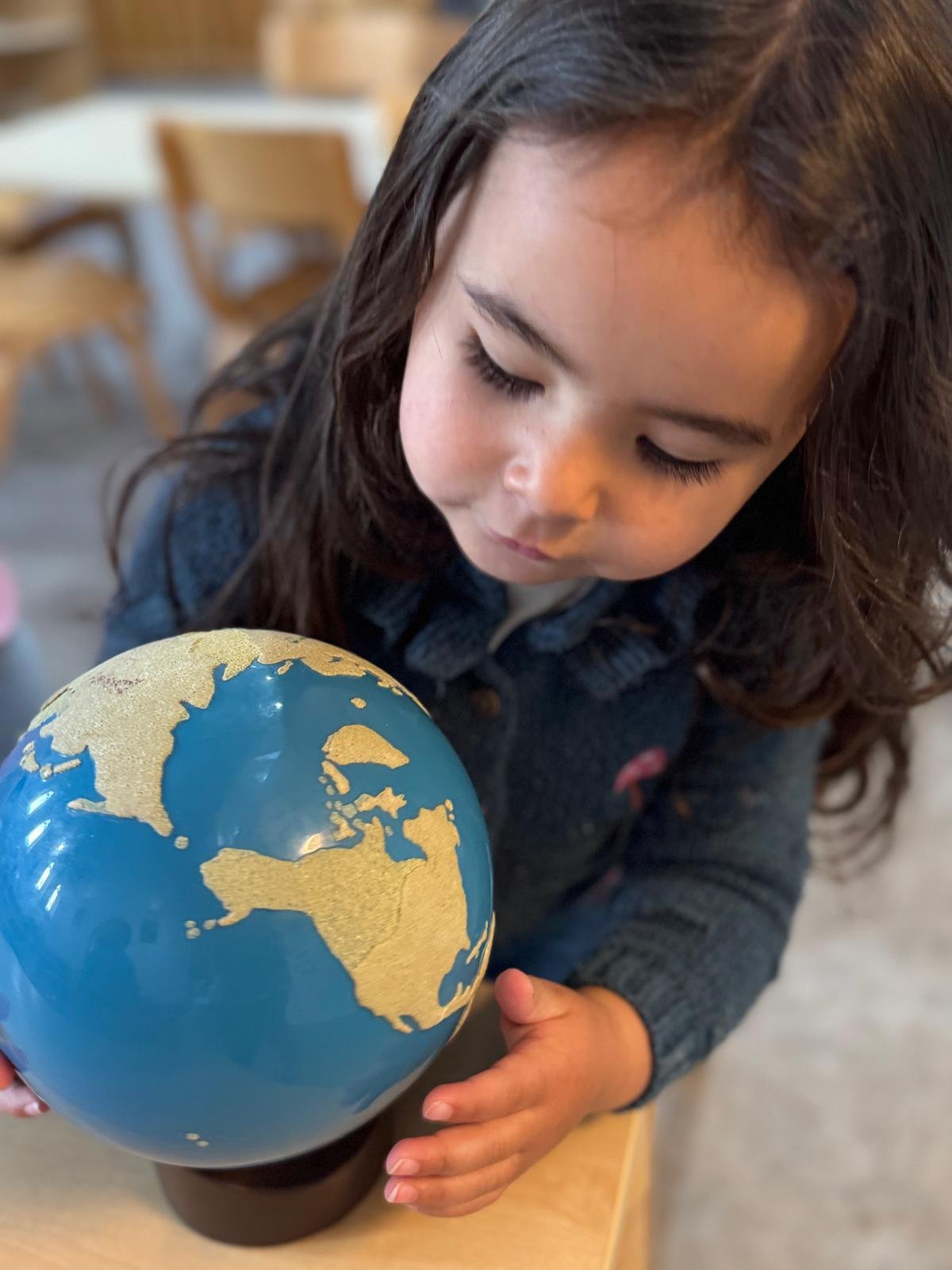 Young child looking at and holding a small globe.