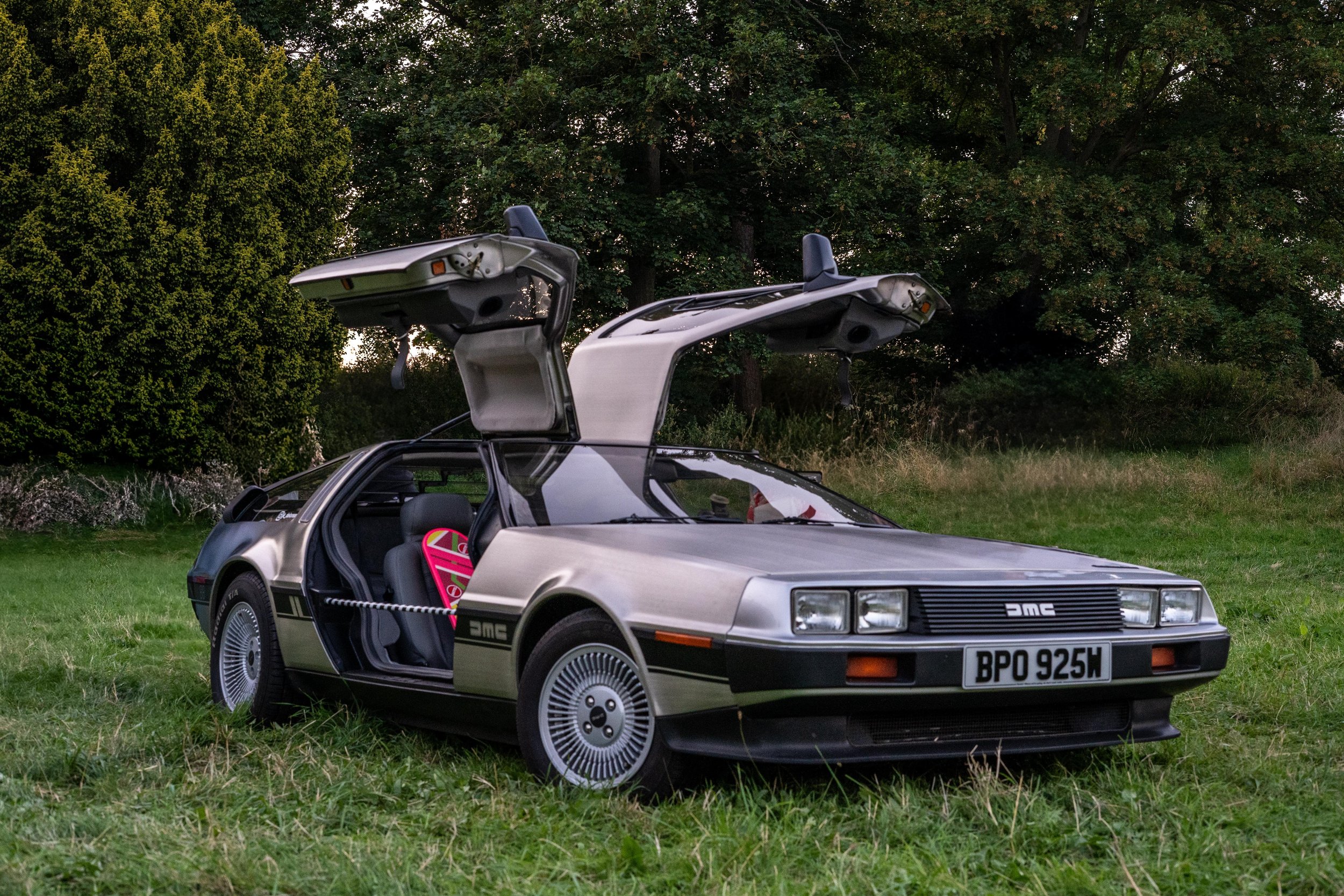 DeLorean DMC-12 with open gull-wing doors in a grassy field
