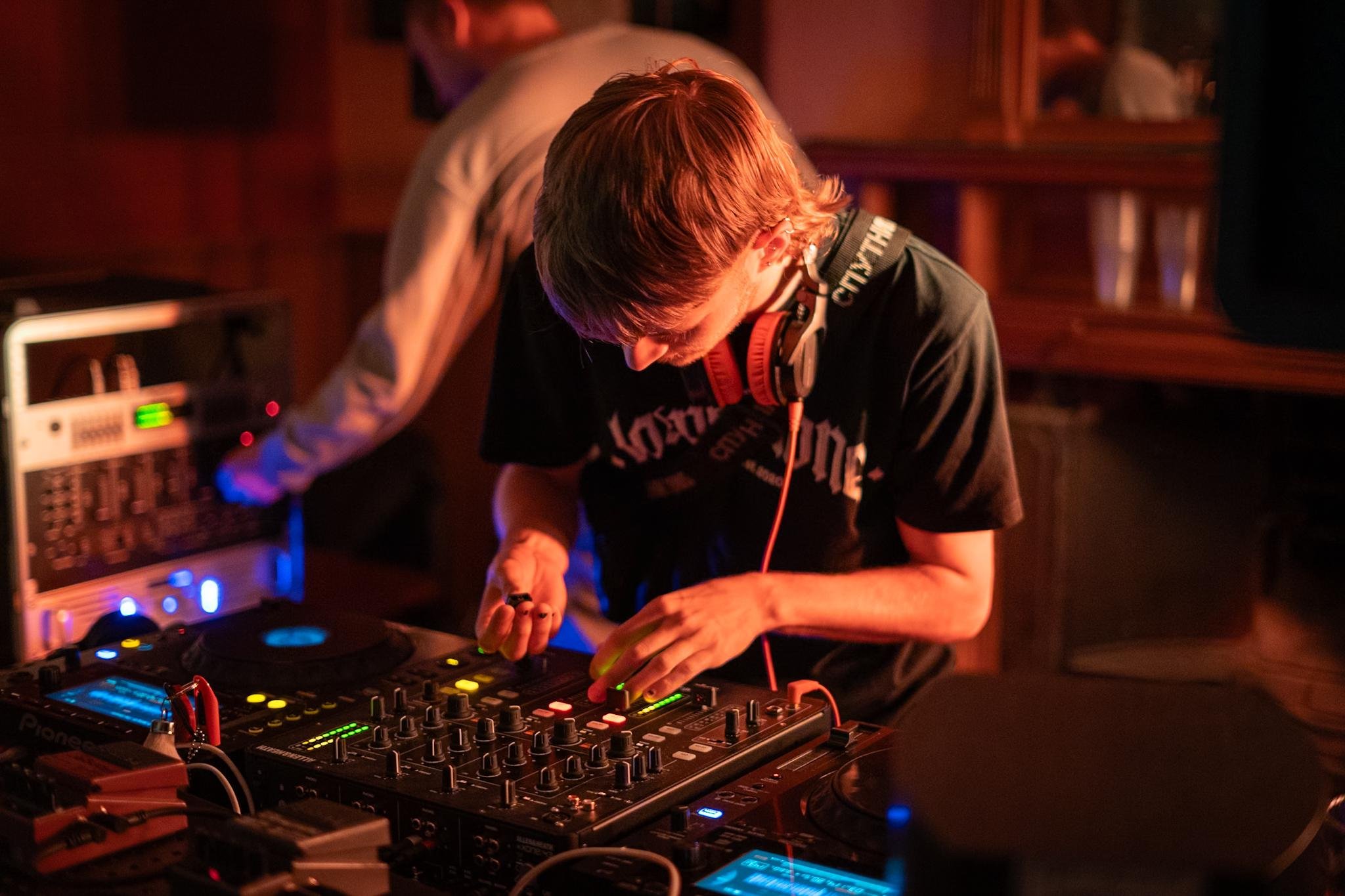 DJ performing at a nightclub with headphones and mixing console