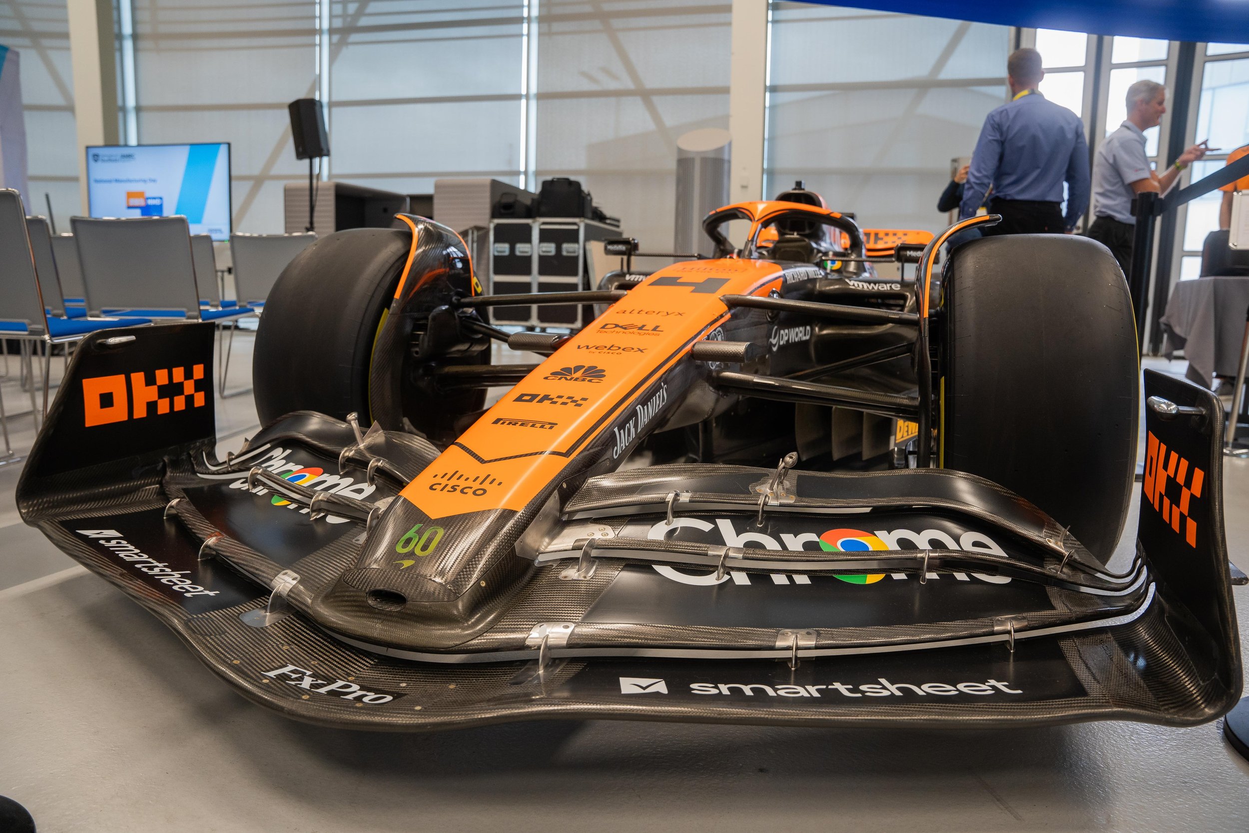 Close-up of a Formula 1 car showcased indoors with visible sponsors like Chrome, Cisco, and Jack Daniels on its body.