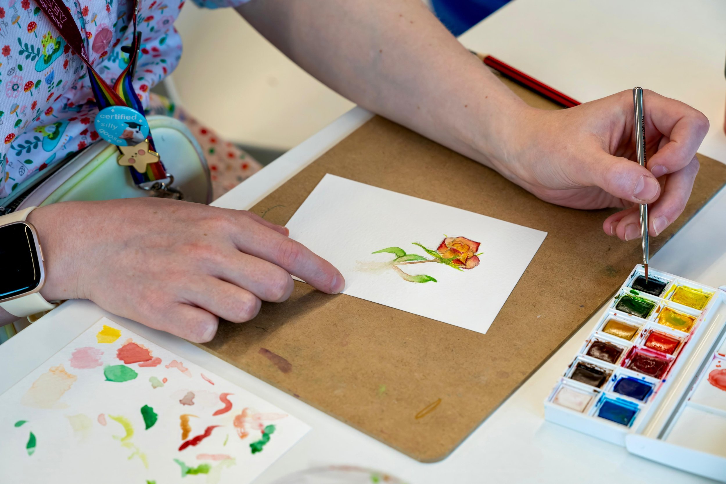 Person painting a flower with watercolors on paper