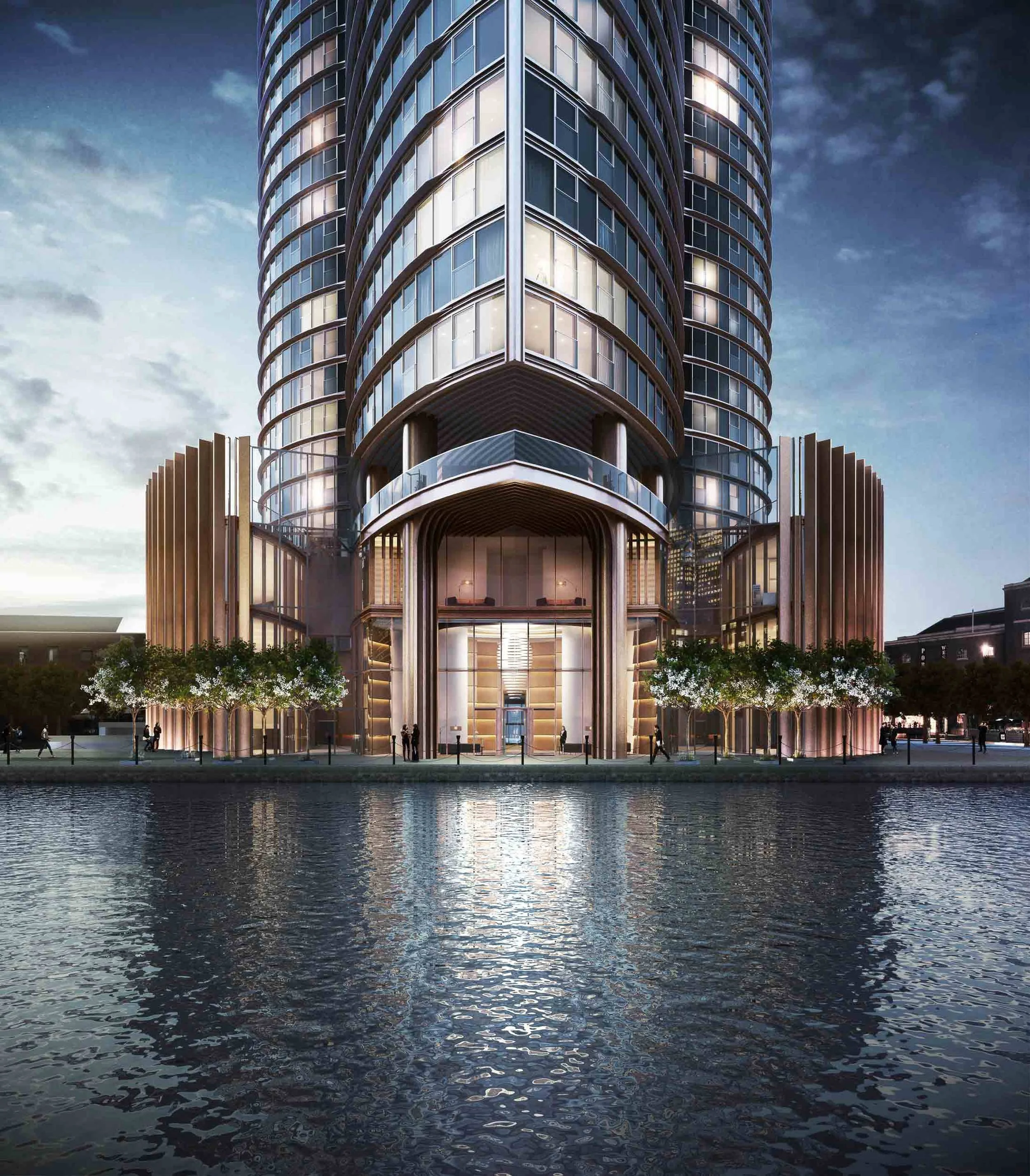 West India Quay with glass facade, waterfront view, and illuminated entrance at twilight.