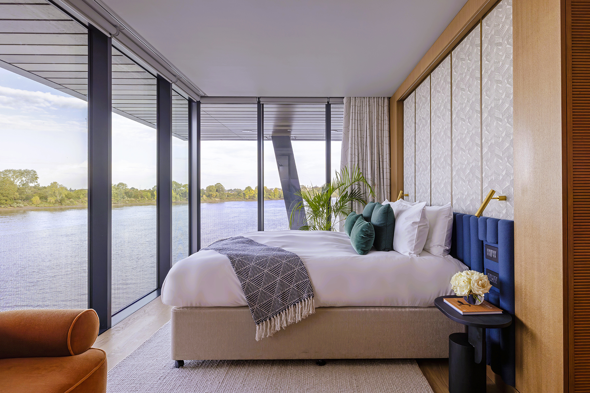 Fulham Pier Hotel at sunset with modern furniture, fire pit, pergola covered in greenery, and view of a serene lake.