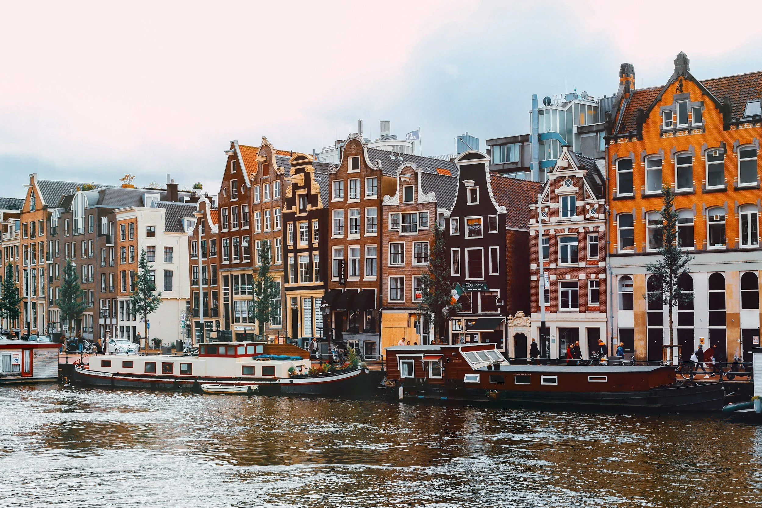 Une rangée de bâtiments historiques colorés le long d'un canal, avec des bateaux amarrés au premier plan, dans une ville européenne.
