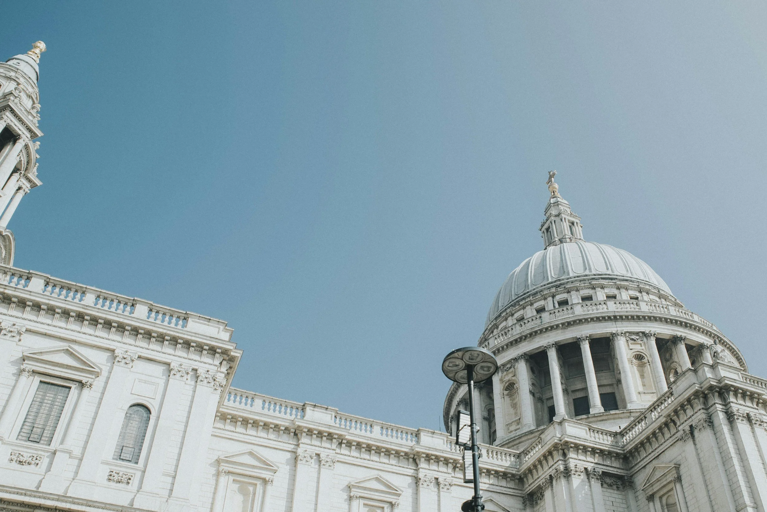 Une vue en contre-plongée de la basilique Saint-Paul, un monument emblématique de Londres, avec un ciel bleu clair en arrière-plan.