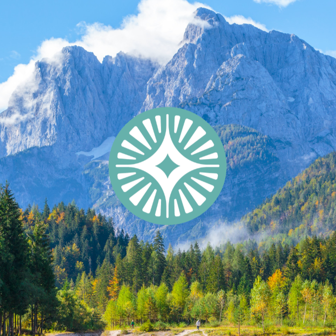 Montagne majestueuse avec forêt flottante au premier plan, ciel bleu avec quelques nuages.