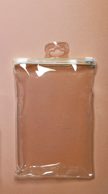 Sac en plastique transparent avec zip et crochet de suspension, vide, posé sur une surface rose