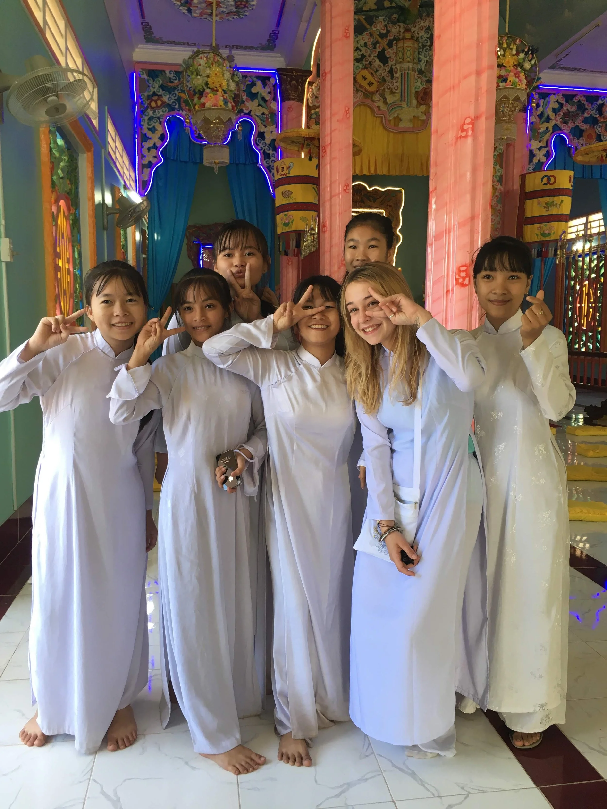 Groupe de jeunes filles en robe blanche posant dans un lieu coloré avec des décorations et des lumières