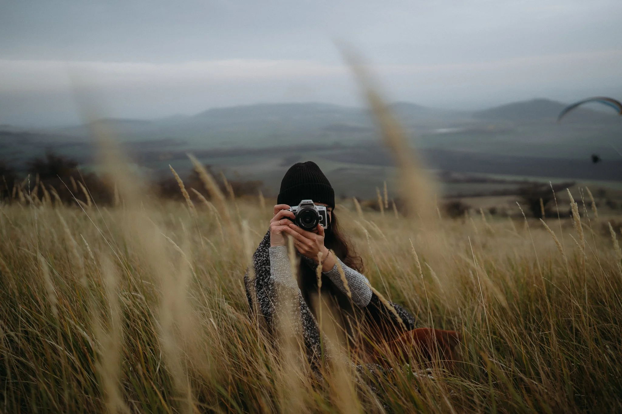 Portrét fotografky na kopci Raná v Českém středohoří při podzimním focení, zamračená obloha, lifestyle.