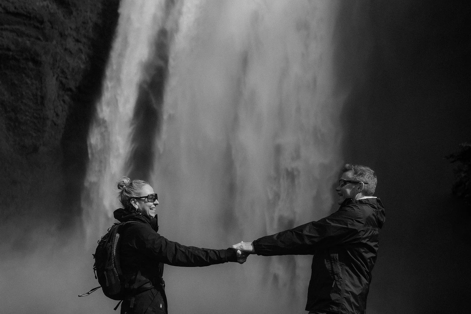 Párové focení před vodopádem Skogafoss na Islandu. Černobílá fotografie. Spontánní focení turistů.