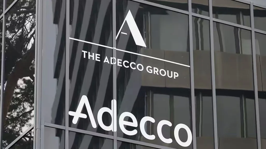 The Adecco Group logo on a glass building facade.