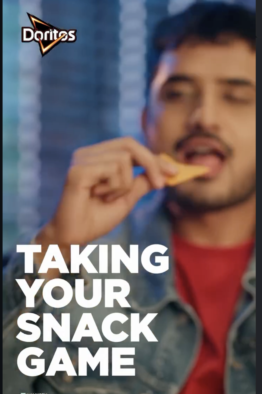 A man eating Doritos chips with a background that appears to be a brick wall. The Doritos logo is in the top left corner, and there is bold white text that reads "Taking Your Snack Game."