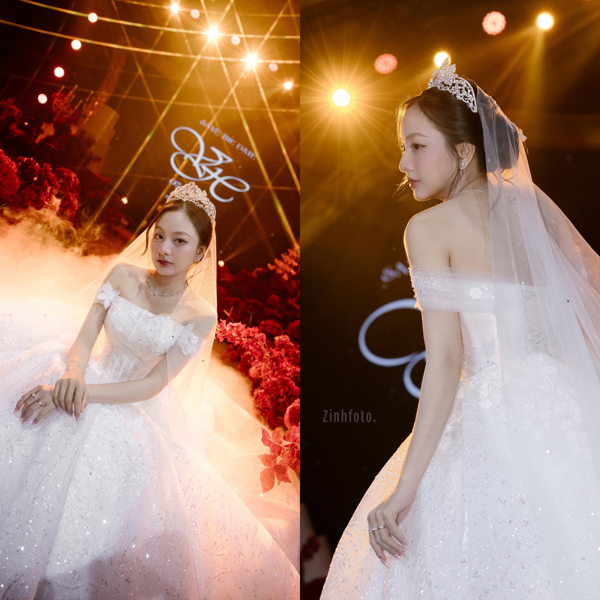 A bride in a white wedding gown with a veil and tiara, posing at a wedding reception with warm lighting and decorative floral arrangements.