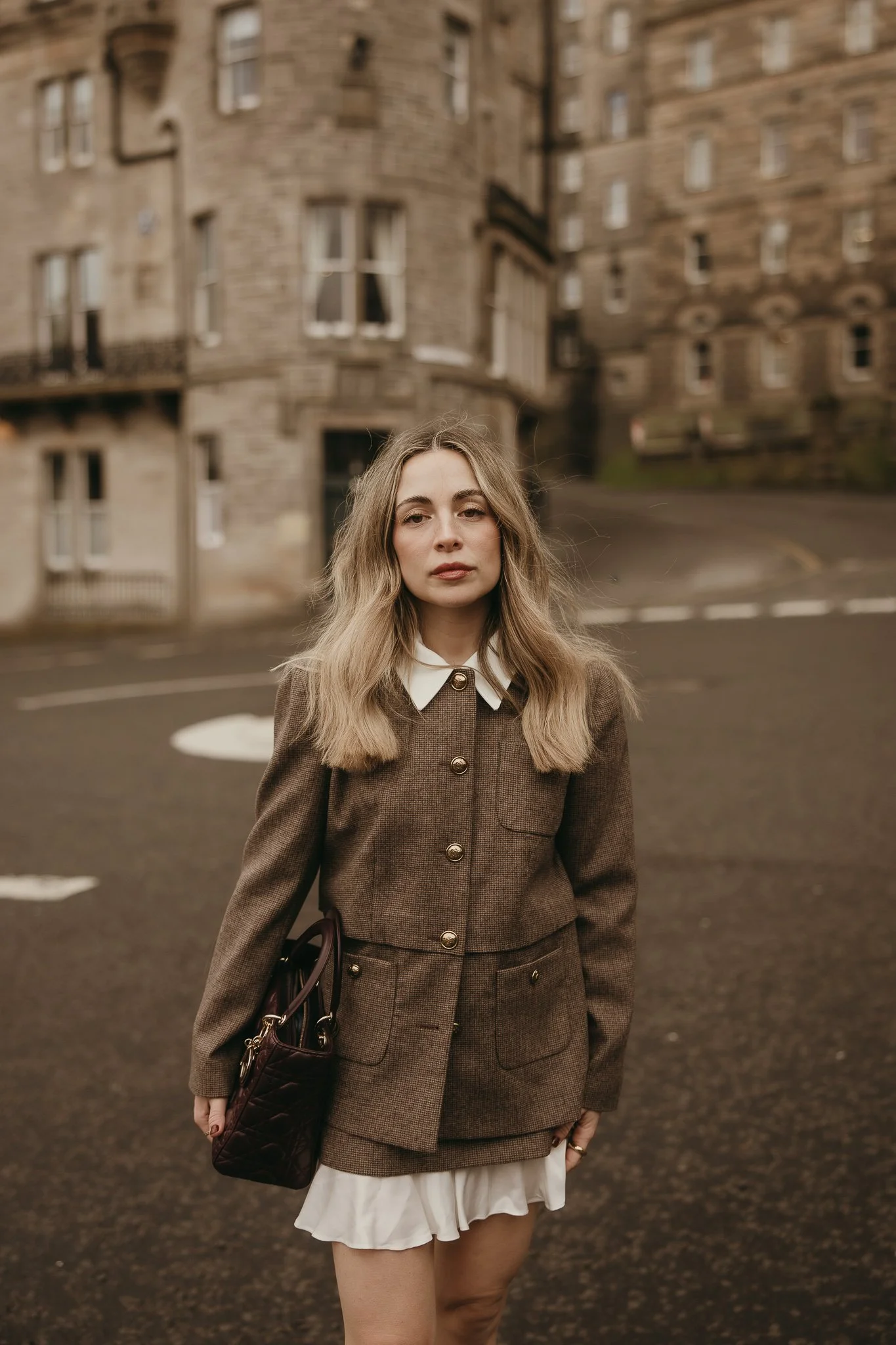 Girl running through historic Edinburgh streets during a cinematic solo travel photography session.