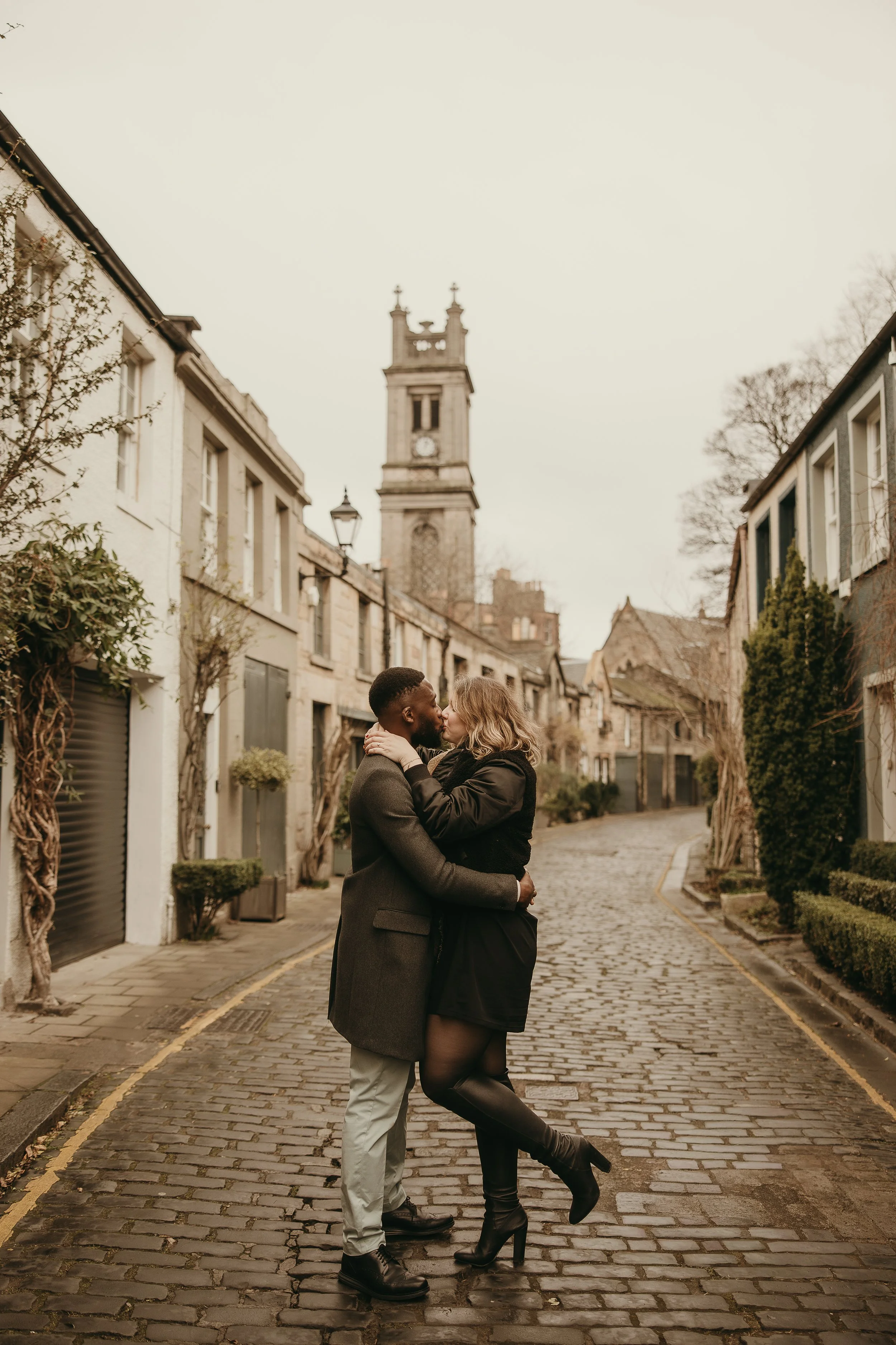 Romantic engagement photoshoot in Edinburgh during golden hour with kissing couple and soft light at Circus Lane