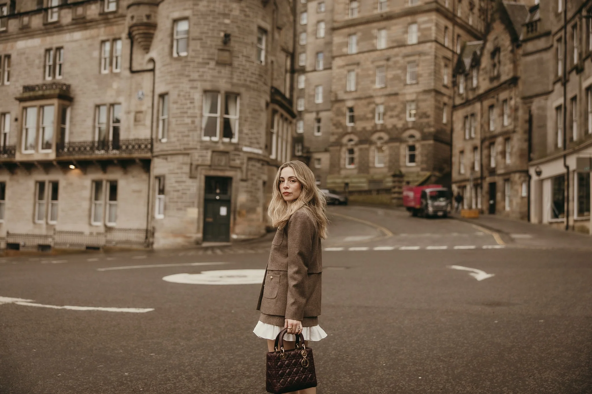 Solo traveler walking through the historic streets of Edinburgh during a romantic solo photoshoot.