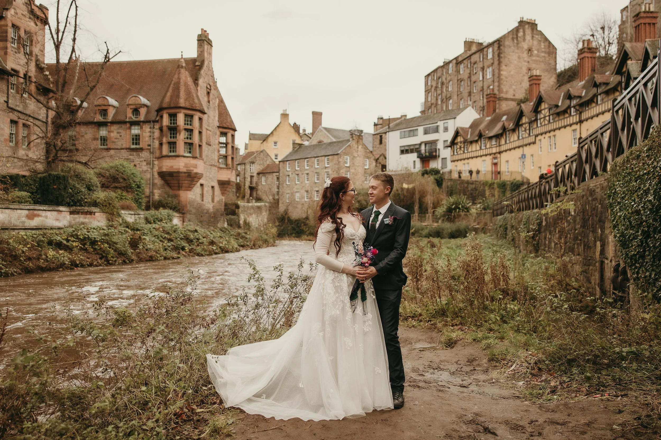 bride and groom walking down the streets in Edinburgh holding their hands and holding vintage flowers.