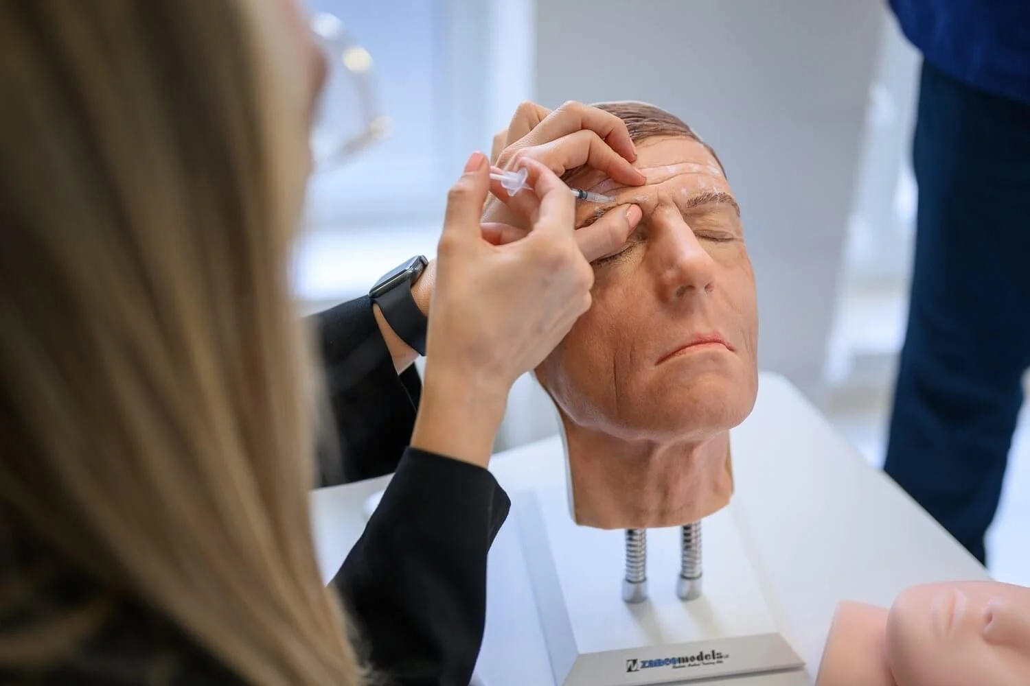 Trainer holding practice head during aesthetics course