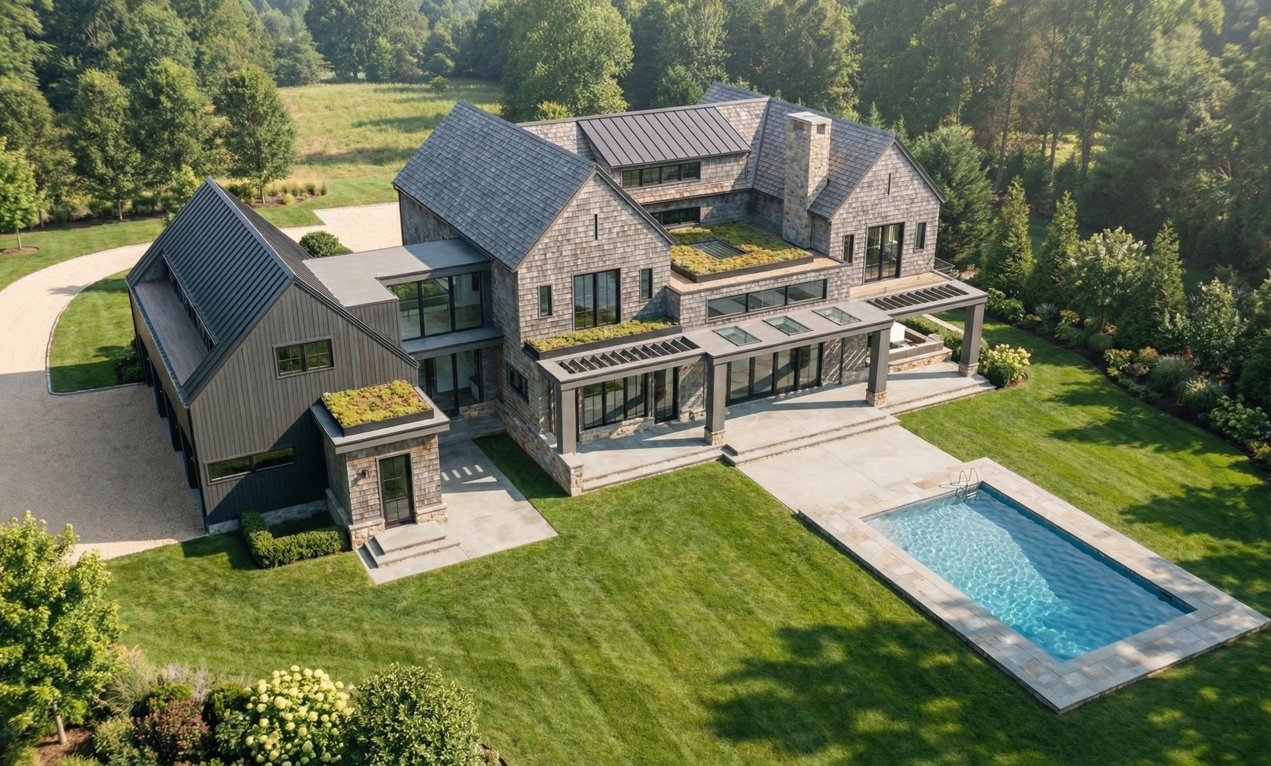 A large modern house with gray and black exterior, multiple roof sections, large windows, a landscaped backyard with a pool, and surrounded by trees and greenery.