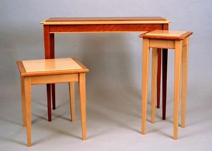 Set of three wooden tables of different heights on a gray background.