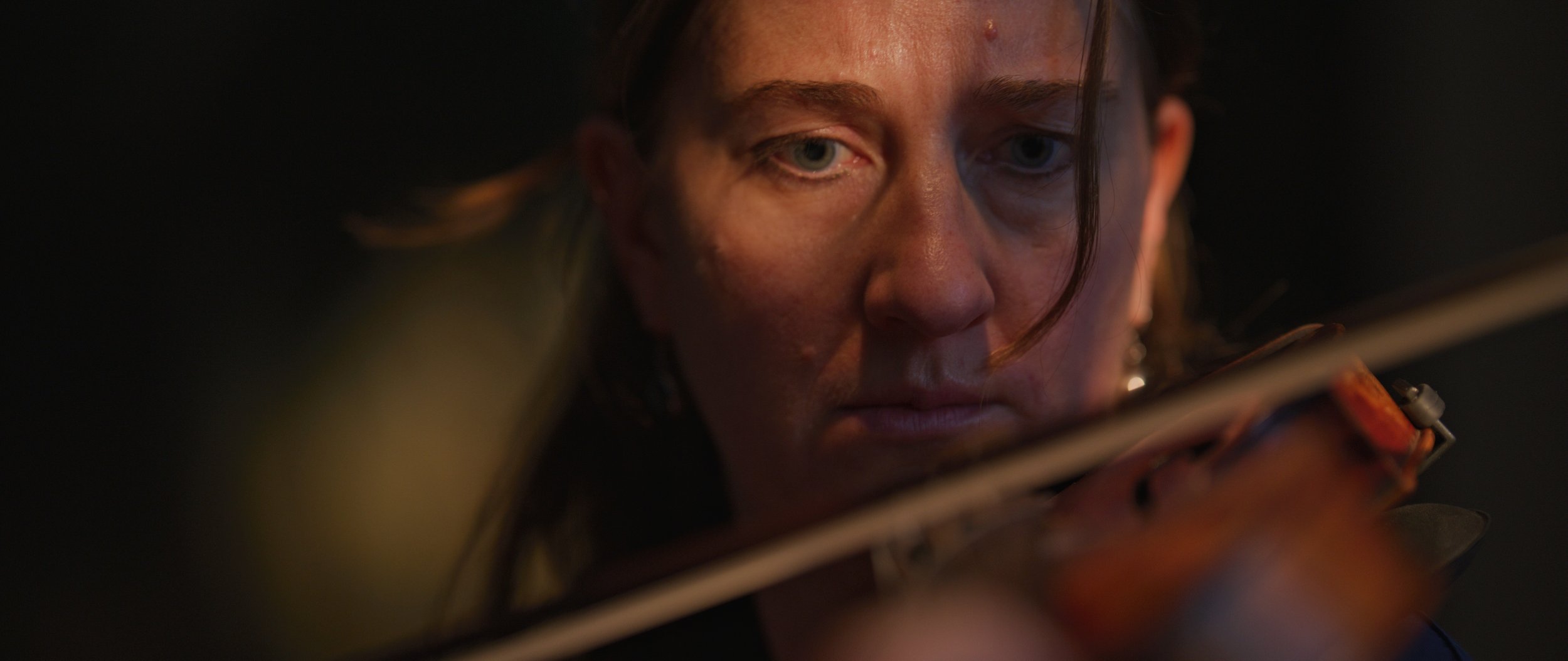 Close-up of a person focused while playing a violin.