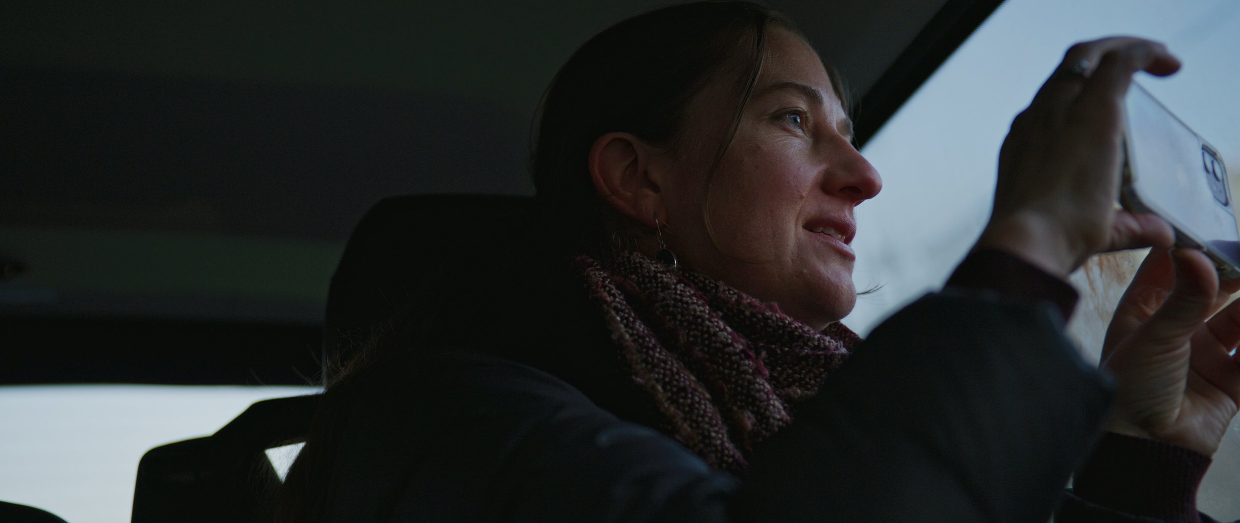 Person sitting in a car holding a smartphone.