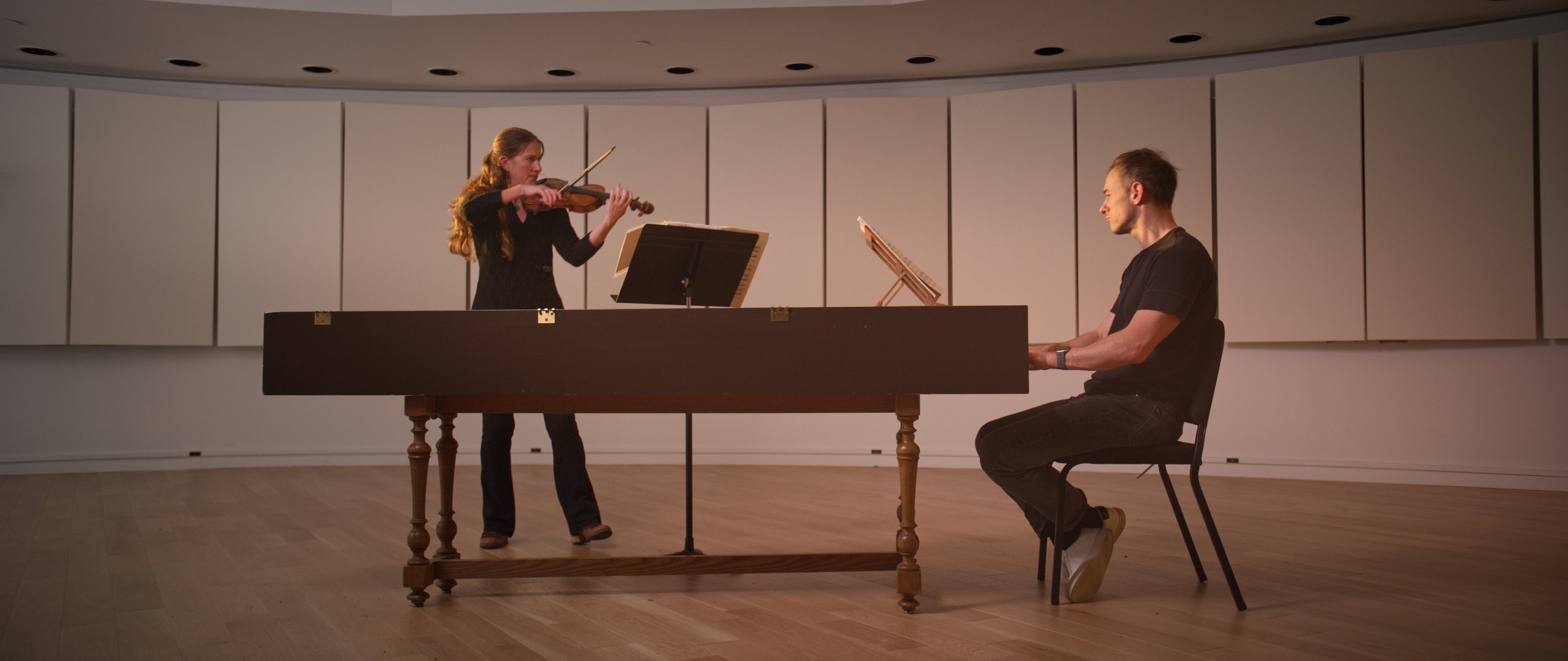 Music rehearsal with woman playing violin and man at harpsichord in studio
