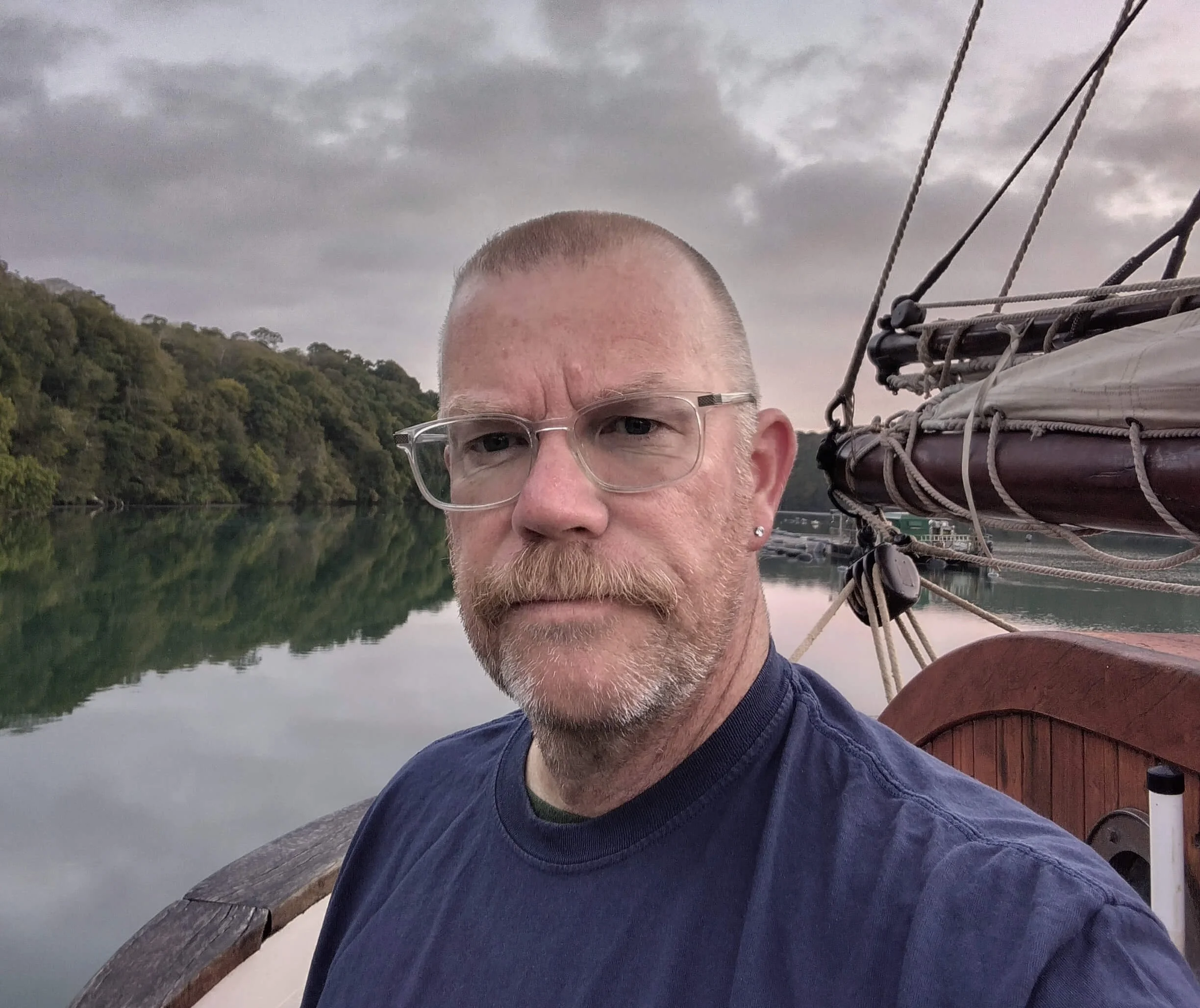 Phil Collier with a calm river and forested hills in the background.