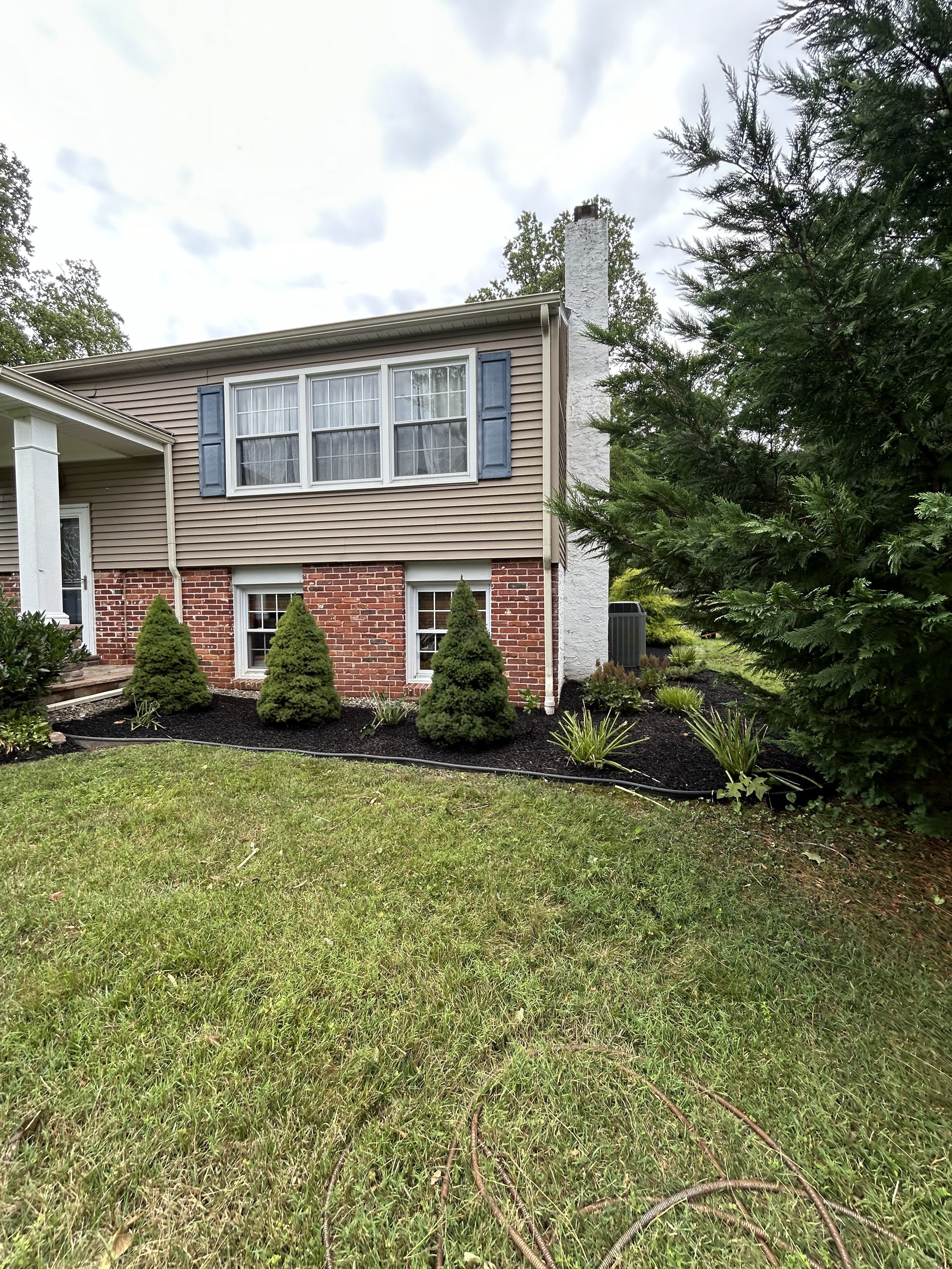 Suburban house with brick and siding exterior, landscaped garden, and green lawn